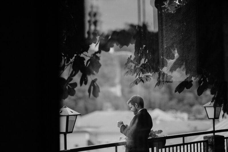 Wedding photography portfolio in Italy: A man in a tuxedo stands on the veranda of the hotel