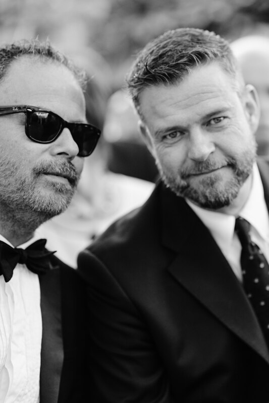 Wedding photography portfolio in Italy: A man looks into the photographer’s lens and sits next to him man in black glasses