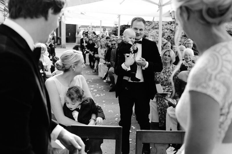 Wedding photography portfolio in Italy: A man holds a little boy in a black tuxedo in his arms