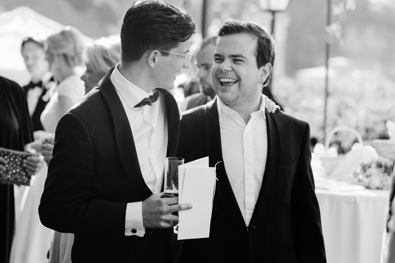 Wedding photography portfolio in Italy: Two men in black tuxedos are smiling at each other