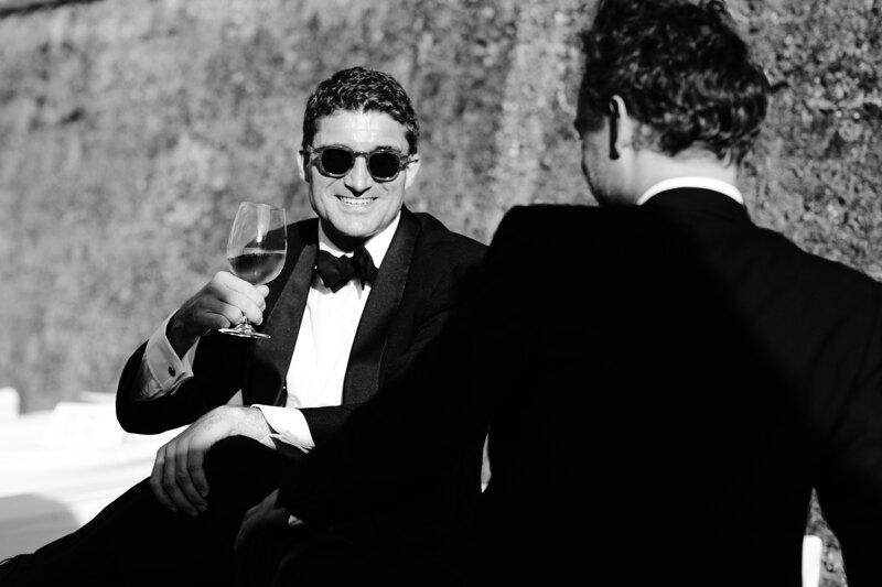 Wedding photography portfolio in Italy: Two men chatting with each other and drinking champagne
