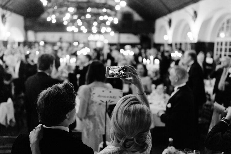 Wedding photography portfolio in Italy: The bride photographs guests in the hall on her phone