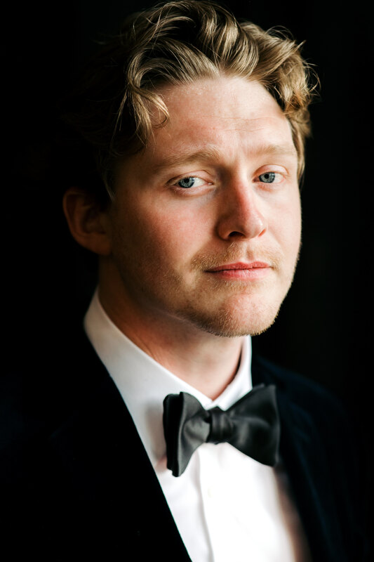Wedding photography portfolio in Italy: Portrait of a groom in a black tuxedo and a bow tie on his neck, with curly hair
