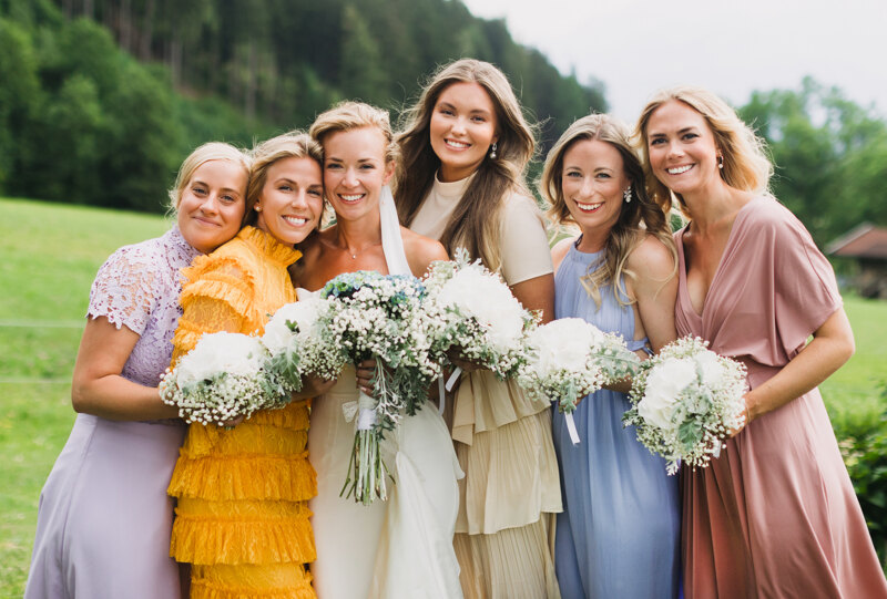 Wedding photography portfolio in Italy: Bride with friends look at the photographer’s camera, hold bouquets in their hands