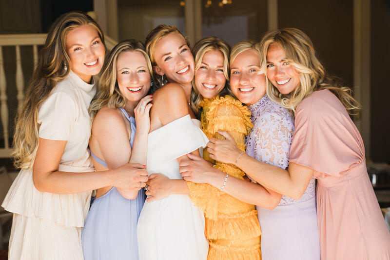 Wedding photography portfolio in Italy: Bride with her friends hugging and smiling at the photographer’s camera