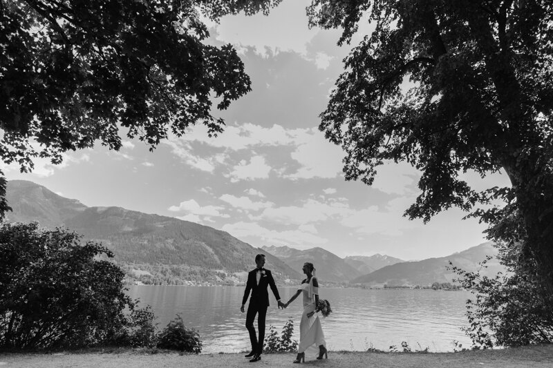 Wedding photography portfolio in Italy: A couple of newlyweds hold hands on a background of a mountain lake