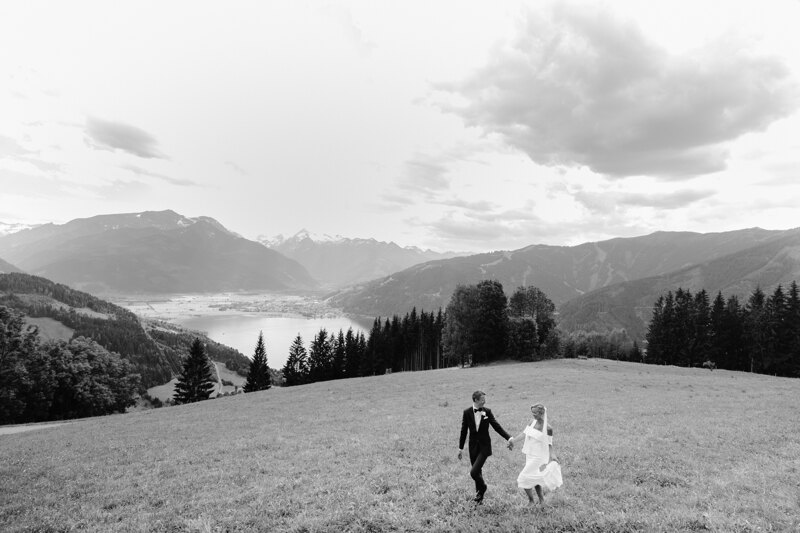Wedding photography portfolio in Italy: The couple walks in the valley against the backdrop of large mountains and a mountain lake