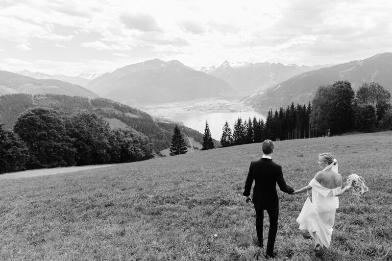 Wedding photography portfolio in Italy: A couple of newlyweds walk in the valley against the backdrop of large mountains and a mountain lake