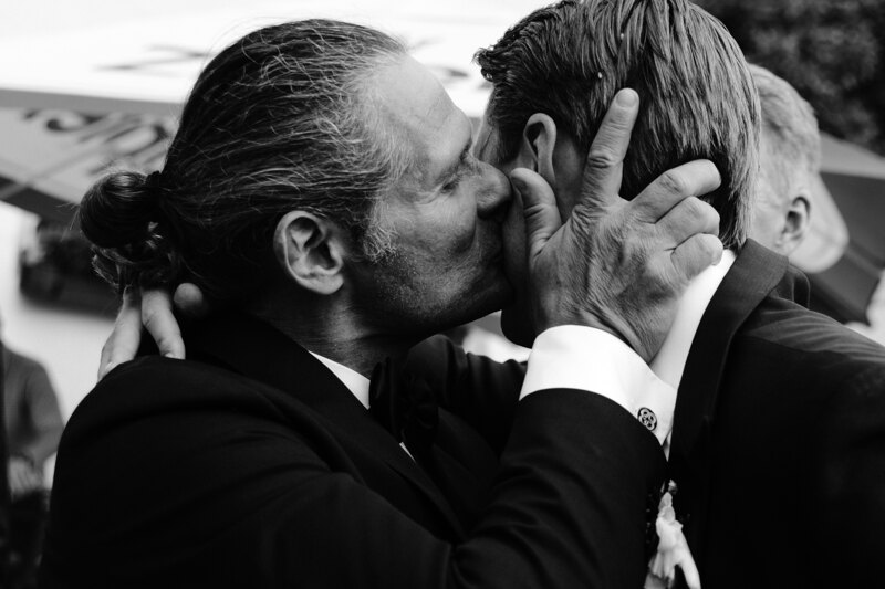 Wedding photography portfolio in Italy: Guest greets the groom and kisses him on the cheek