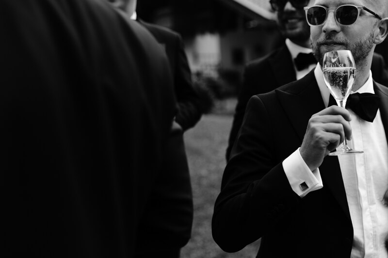 Wedding photography portfolio in Italy: Guest in black glasses drinks champagne