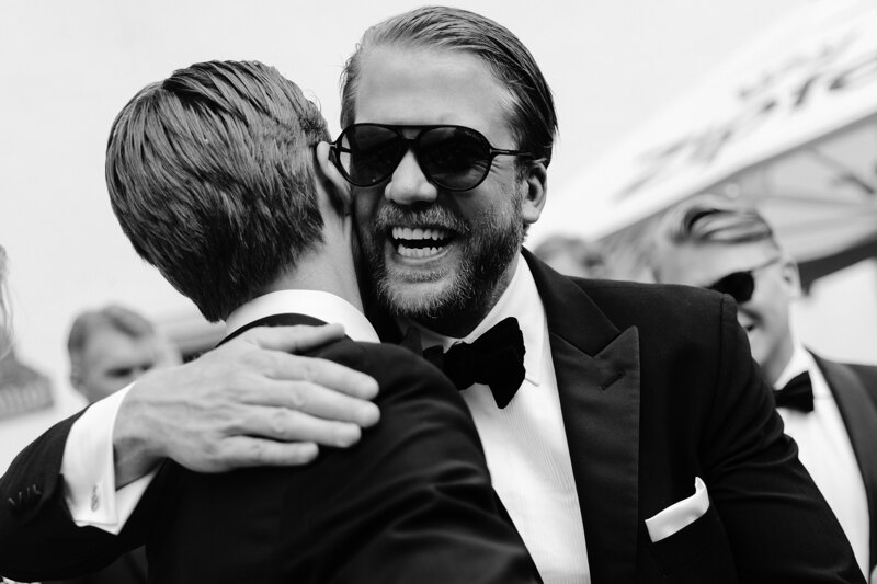Wedding photography portfolio in Italy: The bearded friend of the groom in black glasses hugs the groom