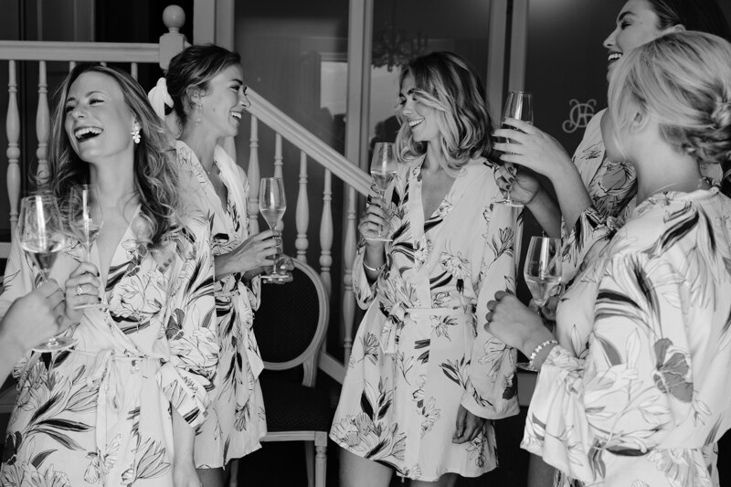 Wedding photography portfolio in Italy: The bride and her friends have fun talking, drink champagne at the morning photo shoot in the hotel room