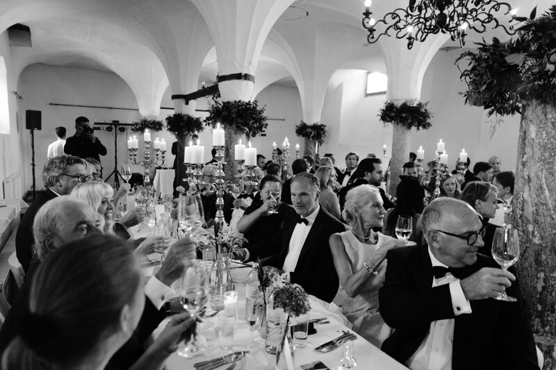 Wedding photography portfolio in Italy: Guests sit at the festive table and raise their glasses for the newlyweds