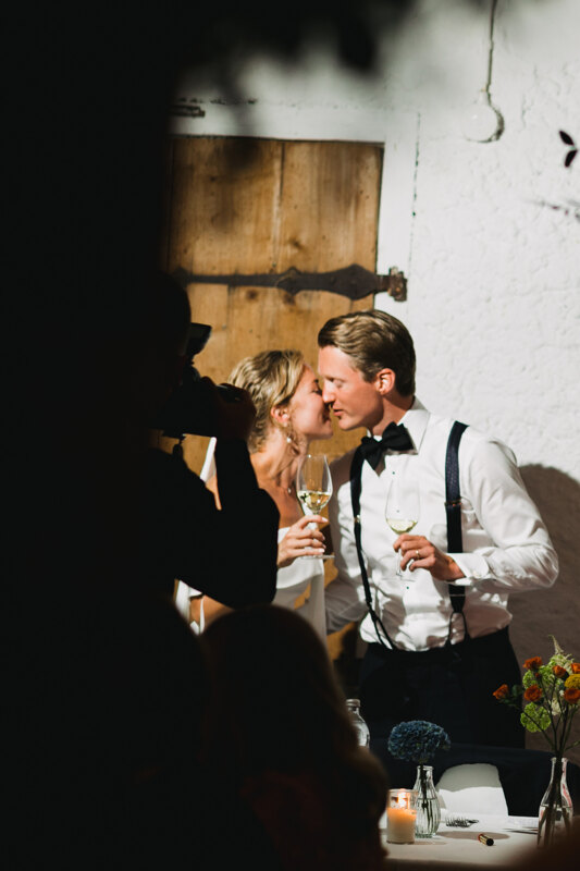 Wedding photography portfolio in Italy: The bride and groom posing for the photographer gently touching their faces and holding wine glasses in their hands