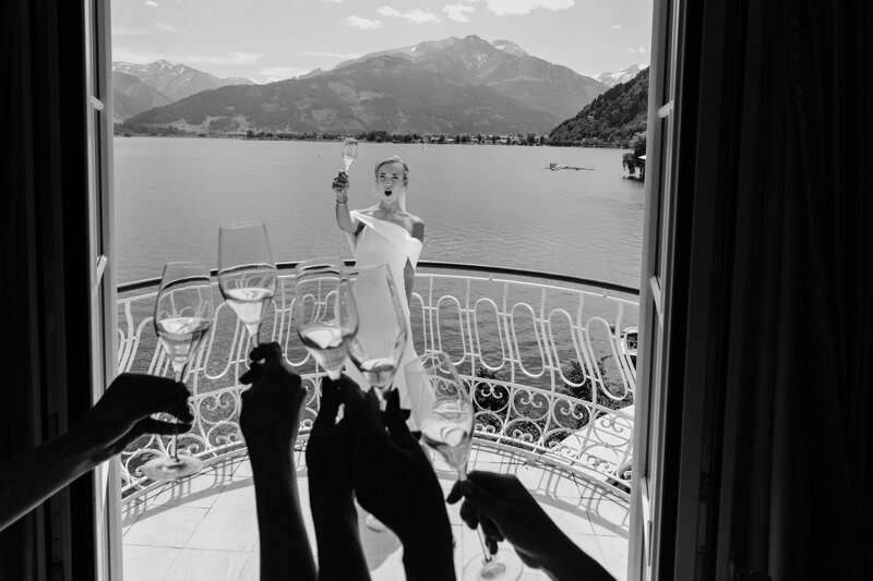 Wedding photography portfolio in Italy: Bride with girlfriends raising champagne glasses on the balcony