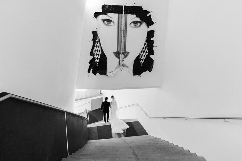 Wedding Photographer in Venice: Bride and groom walking down the gallery stairs holding hands