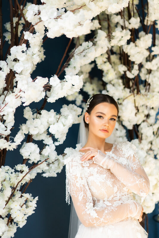 Wedding Photographer in Venice: Fragile and tender bride, in a white, embroidered dress, among white sakura flowers