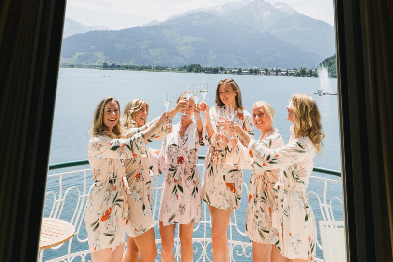 Wedding Photographer in Venice: Morning photo shoot of the bride with her bridesmaids standing on the balcony of a luxury villa on Lake Como and drinking champagne