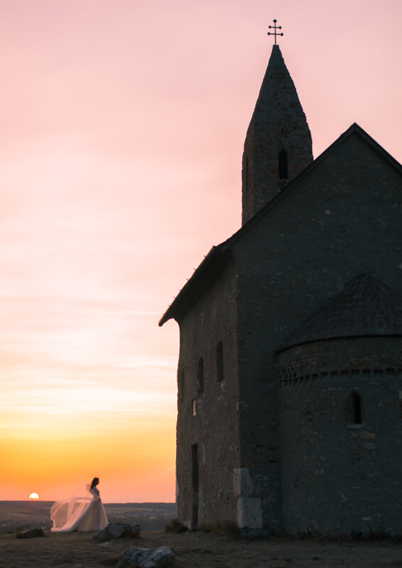 Wedding Photographer in Venice: A tiny bride stands in the background of the setting sun, opposite the old church