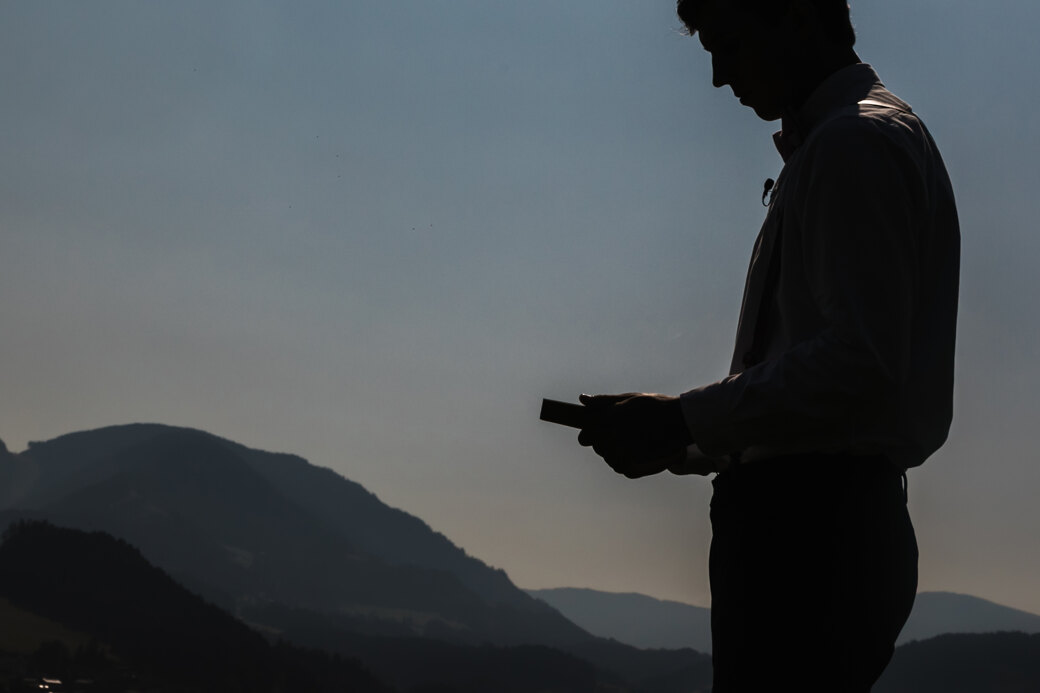  Wedding Photographer in Naples: Black and white portrait of the groom who is holding a book in his hands, on the background of endless and beautiful mountains
