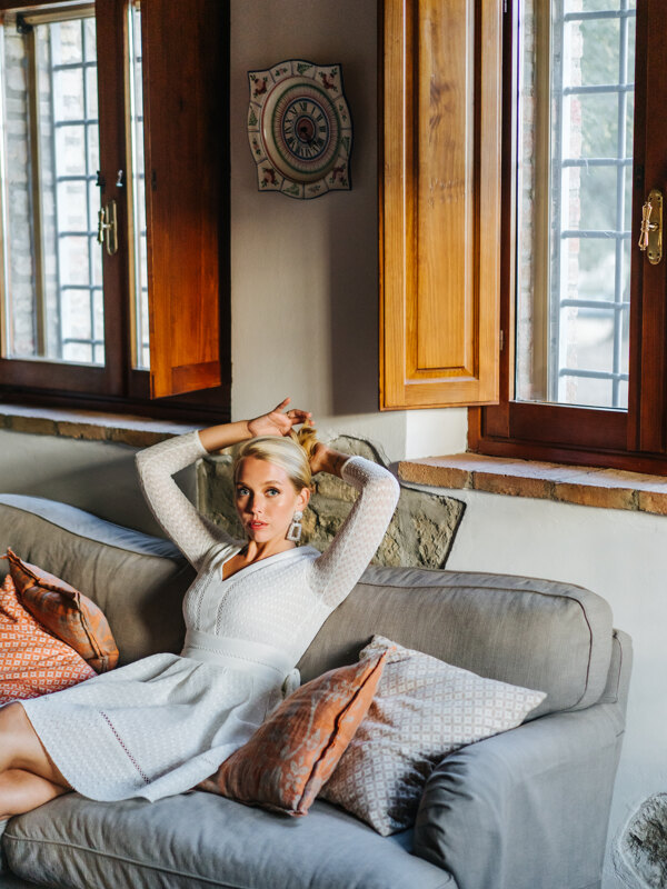 Wedding Photographer in Naples: Bride in a short white dress sitting on a sofa in a hotel room