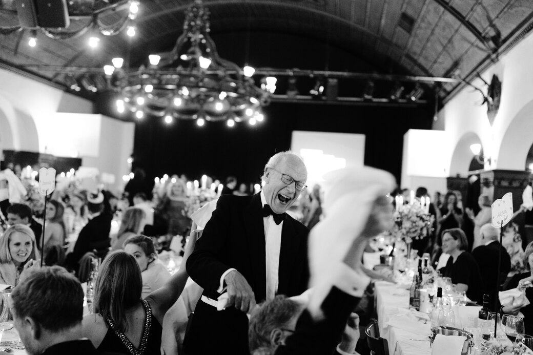 Wedding Photographer in Naples: A solid senior man, sincerely smiles at a wedding in a banquet hall