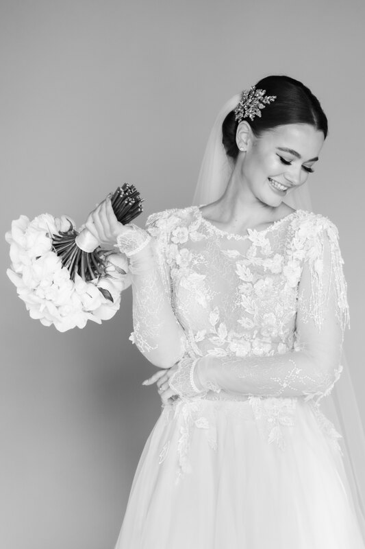 Wedding Photographer in Milan: Black-and-white photo of a bride who smiles and holds a bouquet in her hands