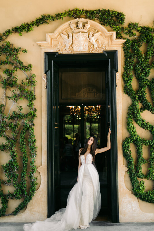 Wedding Photographer in Milan: Bride in dress posing against the backdrop of a building with huge doors