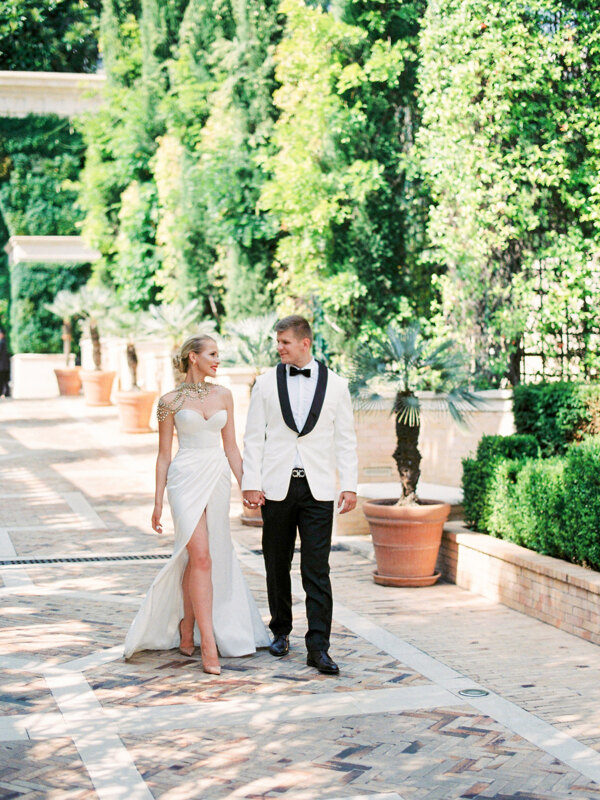 Wedding photography portfolio in Italy: Beautiful couple bride and groom, dressed in a white tuxedo and an expensive elegant dress decorated with stones, walk holding hands holding the streets of Monaco