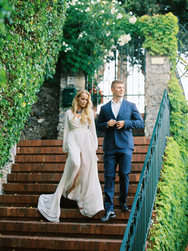 Wedding photography portfolio in Italy: Beautiful couple bride and groom are standing on the stairs at the entrance to the garden
