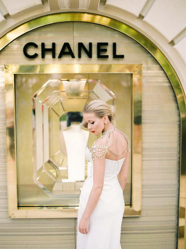 Wedding photography portfolio in Italy: Luxurious bride, in an elegant expensive dress, embroidered with stones, stands against the backdrop of the famous brand Chanel