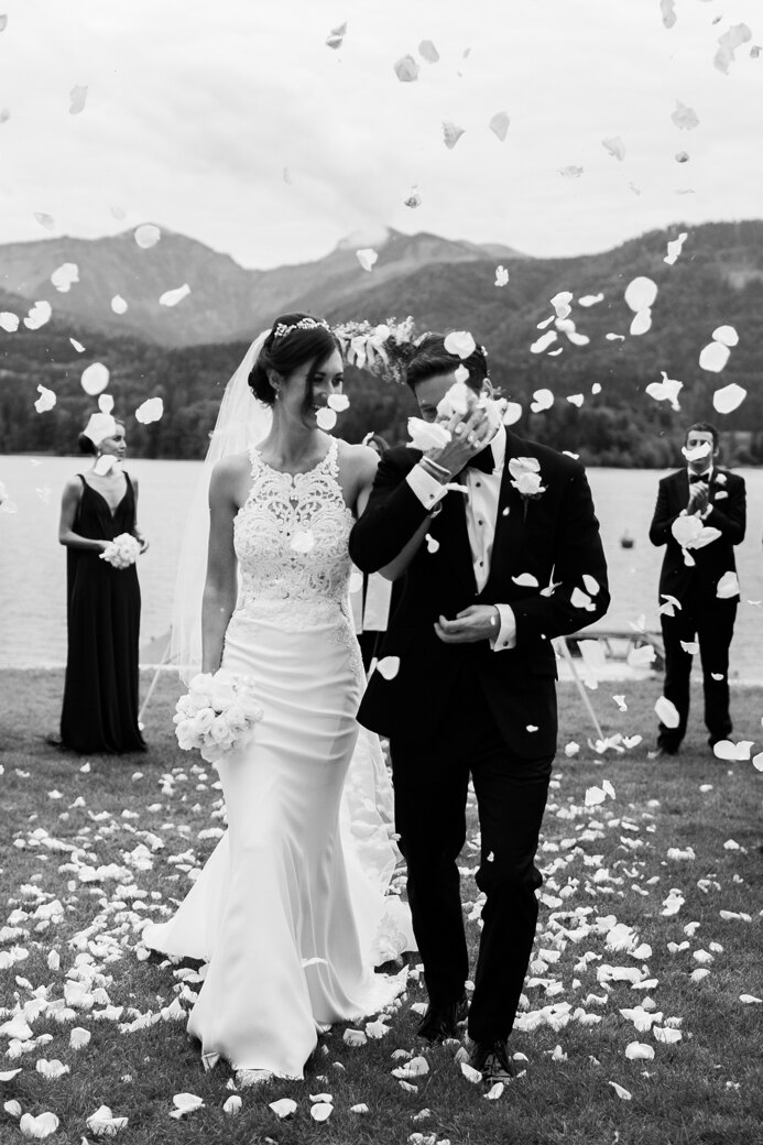 Wedding photography portfolio in Italy: Happy and smiling bride and groom are sent to the banquet hall, after the completion of the wedding ceremony. Guests throw rose petals welcoming a couple with marriage
