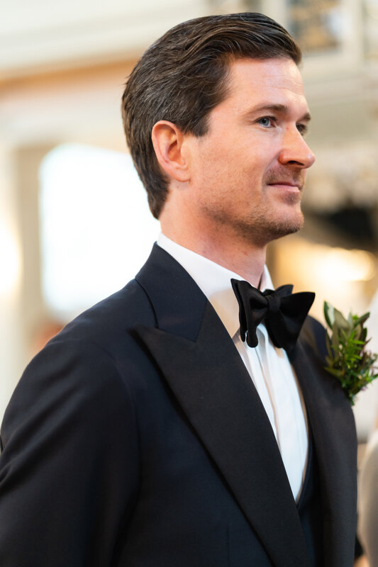 Wedding photography portfolio in Italy: Portrait of a groom in a black tuxedo with neatly laid hair and a buttonhole on a jacket