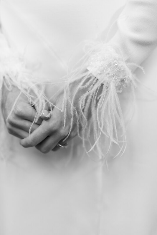 Wedding photography portfolio in Italy: The fragile hands of the bride, which adorn the thin and light feathers on the sleeves of her dress
