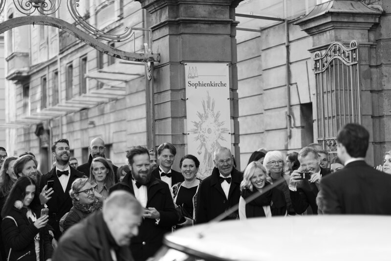 Wedding photography portfolio in Italy: Guests stand near the church and photograph the bride and groom on their mobile phones