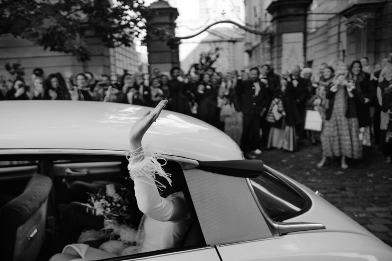Wedding photography portfolio in Italy: The bride waves a hand to guests from the wedding car