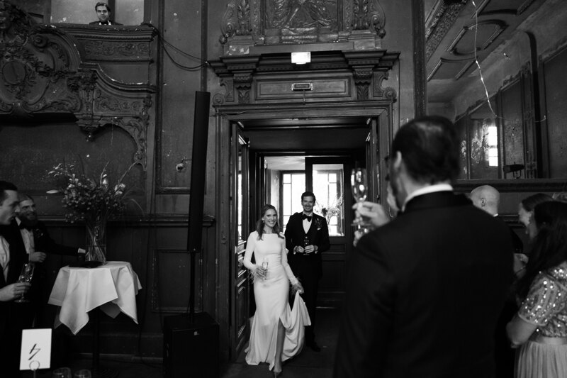 Wedding photography portfolio in Italy: Newly-married newlyweds joyfully and with a smile on their face go into the festive hall where they are greeted by guests