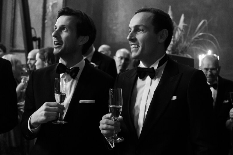 Wedding photography portfolio in Italy: Guests stand with glasses of champagne in their hands in the festive hall