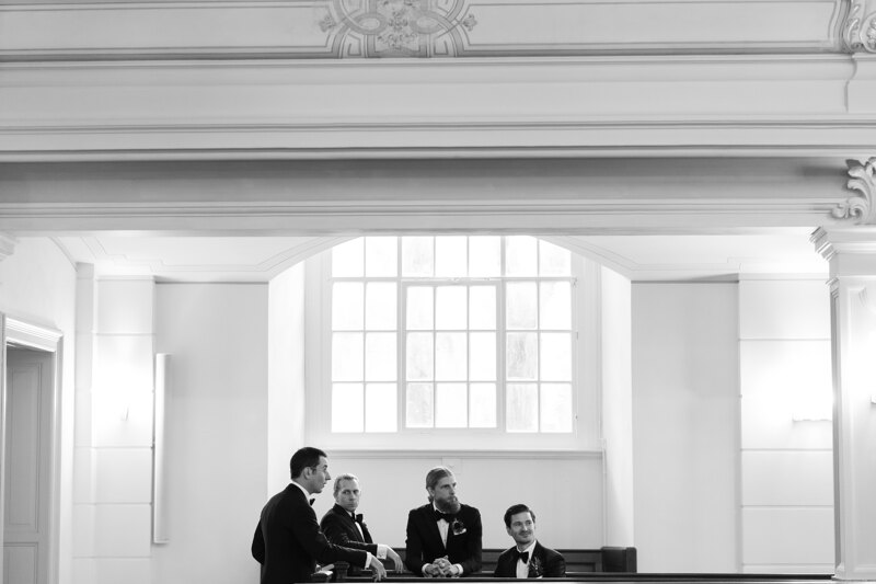 Wedding photography portfolio in Italy: Groom and friends are standing by the window in a large hall