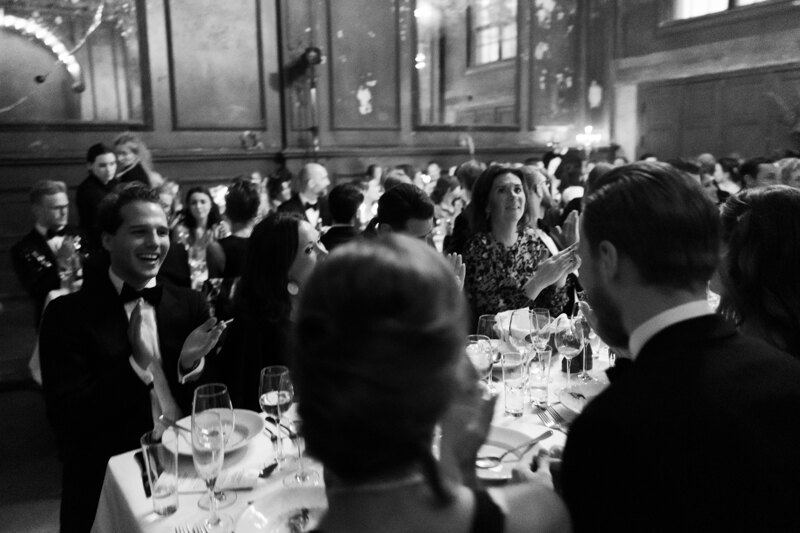 Wedding photography portfolio in Italy: Guests sit at guest tables at a wedding and applaud.