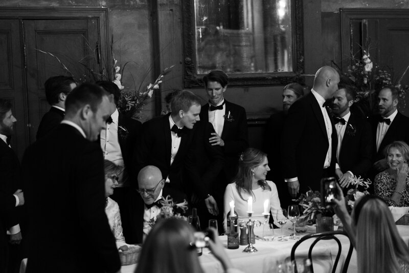 Wedding photography portfolio in Italy: Newlyweds are sitting at a table with guests in the festive hall