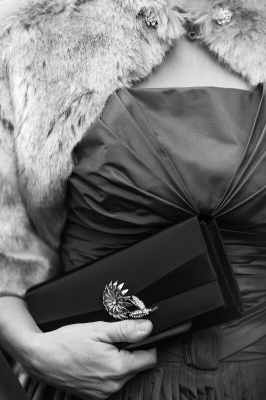 Wedding photography portfolio in Italy: Guest in a dress with a fur cape on his shoulders and a clutch in his hands
