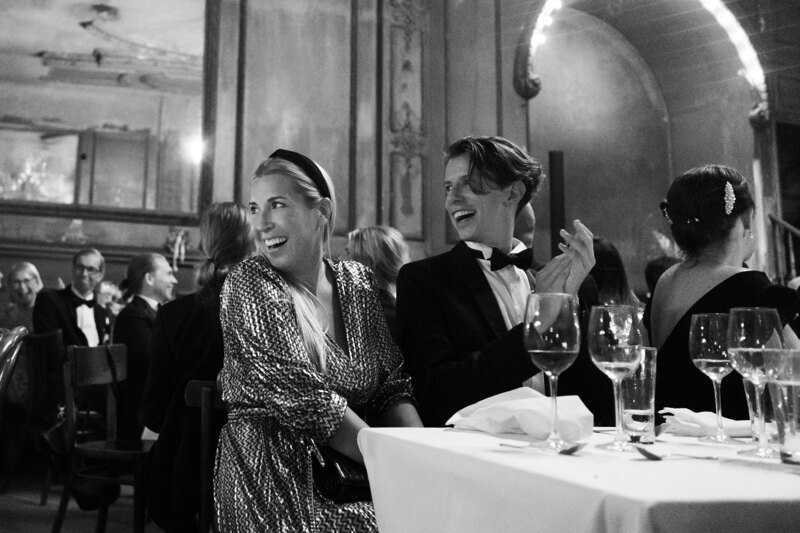 Wedding photography portfolio in Italy: Guests sit at the table, look at the newlyweds, smile and applaud
