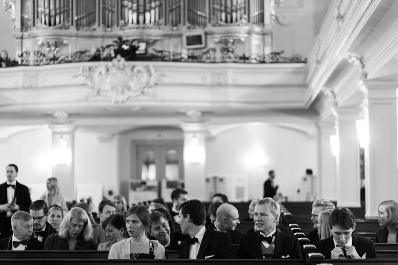 Wedding photography portfolio in Italy: Guests are sitting in the large hall on the benches and expect the ceremony to begin