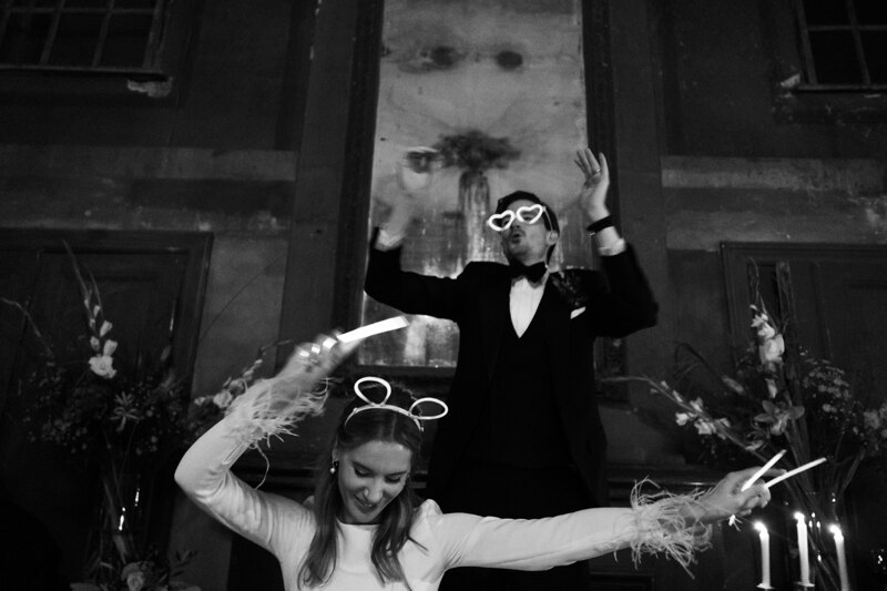 Wedding photography portfolio in Italy: Newlyweds have fun dancing to fiery music, with accessories on their heads and faces