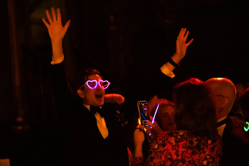 Wedding photography portfolio in Italy: The groom is dancing in heart-shaped curly glasses, guests take pictures of him on the phone