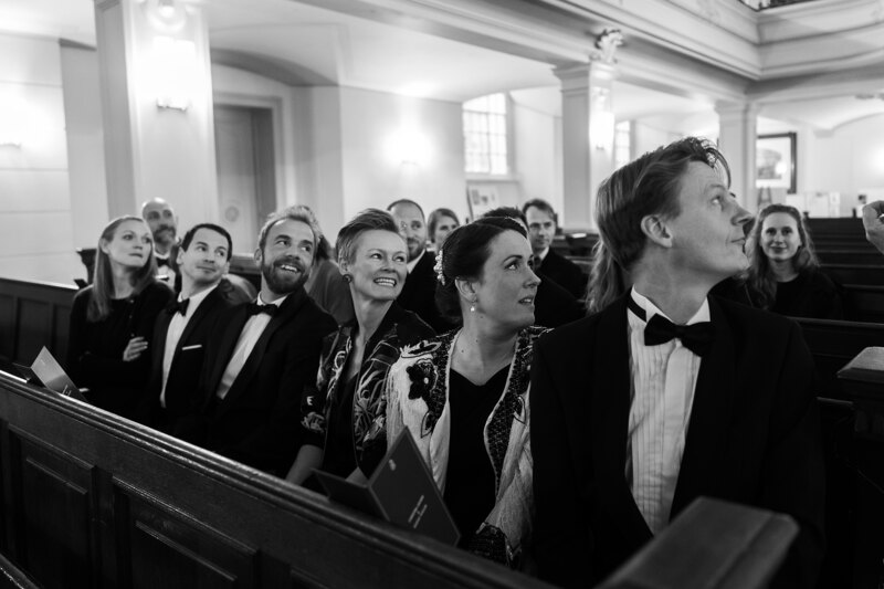 Wedding photography portfolio in Italy: The guests sitting on the benches in the ceremony hall turned their eyes to the side where the bride should come in