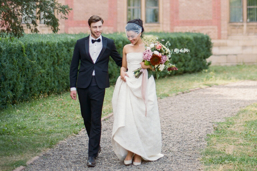 Services of Wedding Photographer in Italy: Happy bride and groom on the background of the residence, walking through the park, holding hands