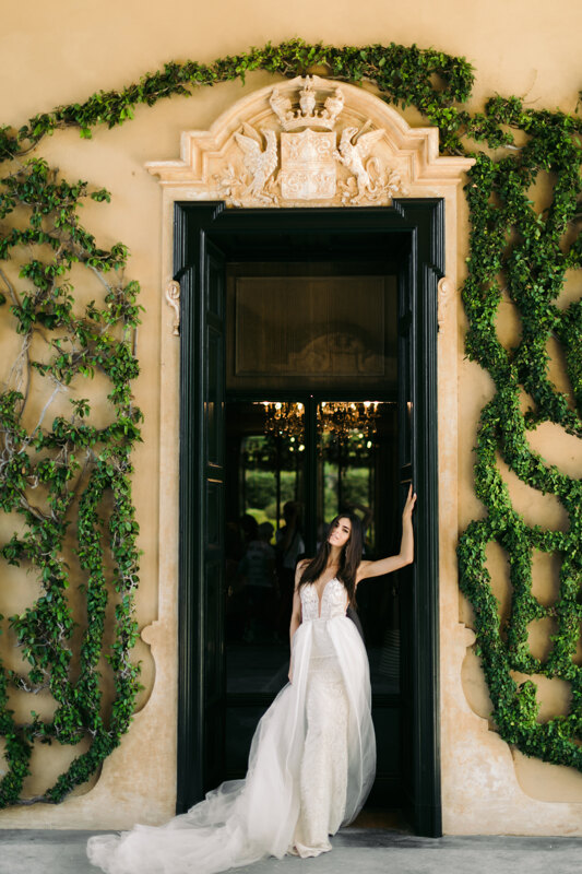Couple photoshoot in Italy: bride in a dress posing against the backdrop of a building with huge doors