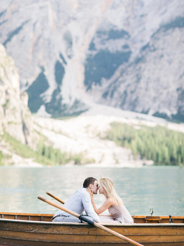 Couple photoshoot in Italy: Loving couple sitting in a boat on a lake in the Dolomites